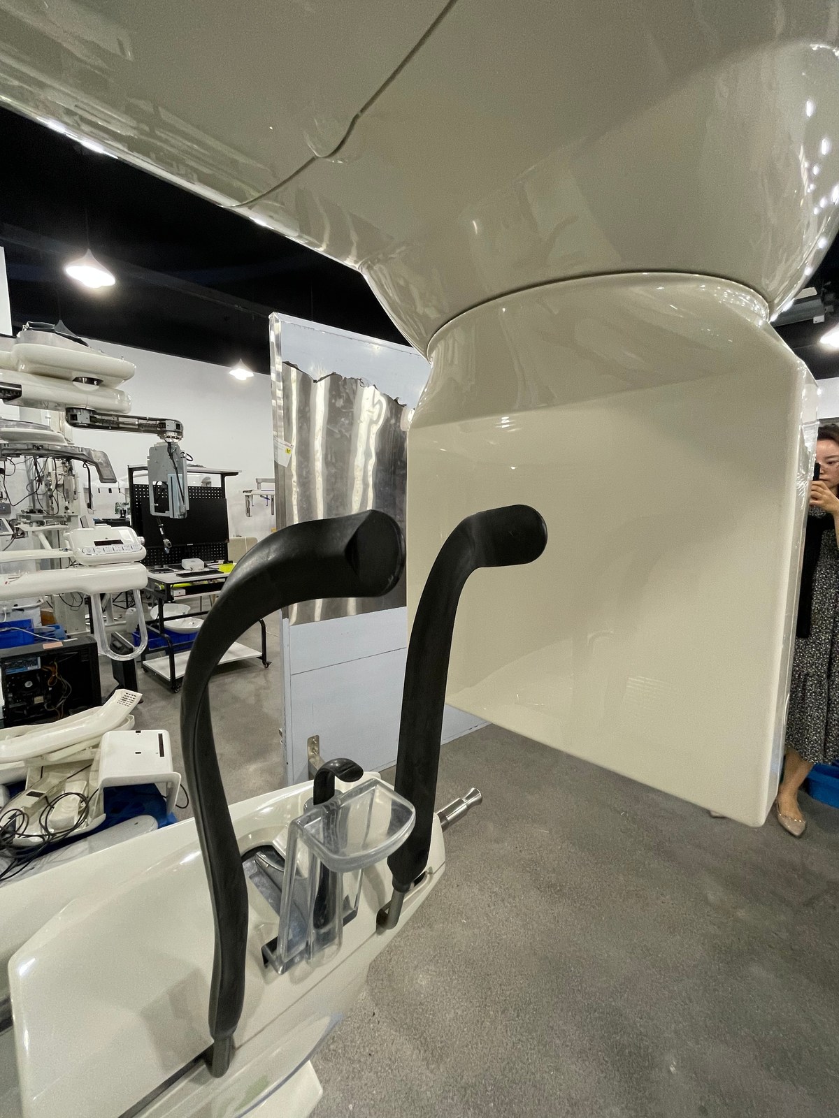 Detail view of the Carestream CS 9300 Select patient positioning system — two shaped rubber grip handles in black, the chin-rest cradle with clear bite-block holder, stainless-steel chin-positioning pin, and the glossy white chassis housing the generator column