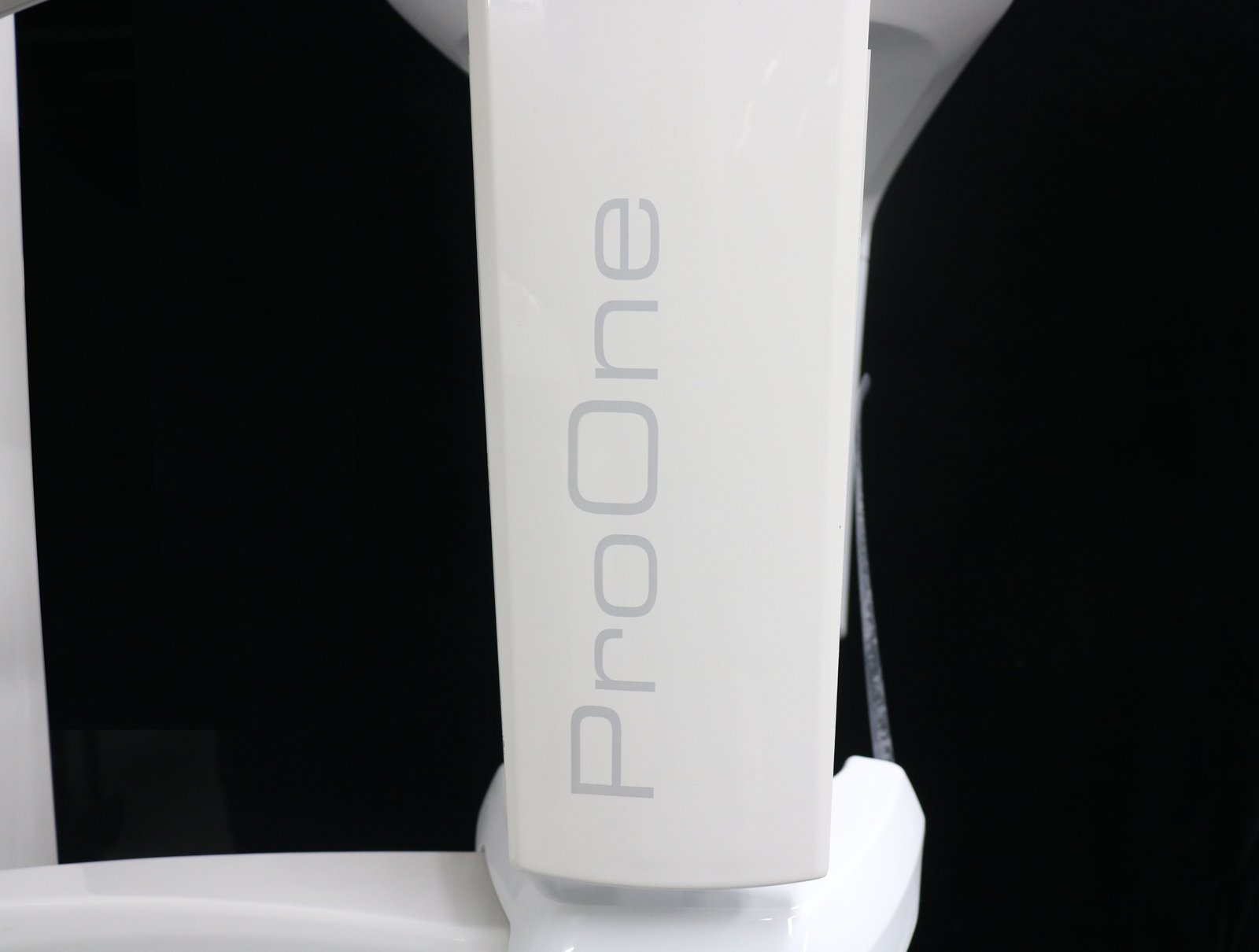 Planmeca-branded imaging sensor head of the ProOne with green exposure-ready indicator button and patient positioning arm