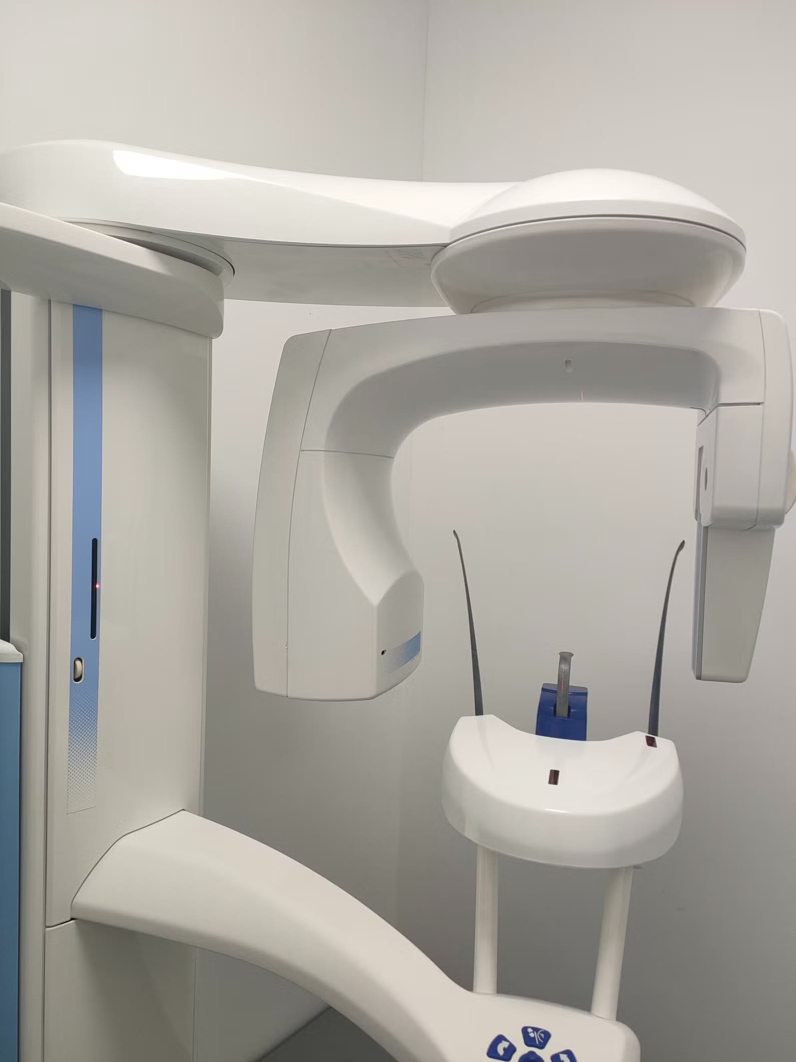 Planmeca ProMax 2D gantry close-up showing C-arm, tube head, chin rest with blue bite block, and signature Planmeca blue column stripe